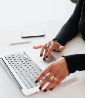 A businesswoman's hands typing on a laptop at a bright, modern workspace.
