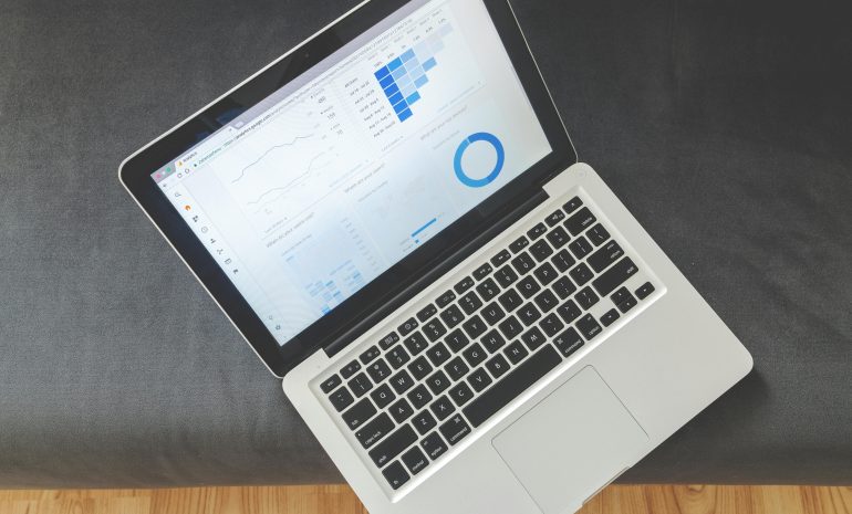 Overhead view of a laptop showing data visualizations and charts on its screen.