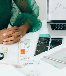 A person analyzes financial charts and graphs at a desk, indicating business trading activity.