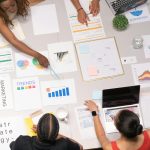 Top view of a team collaborating on marketing strategy and analysis papers.