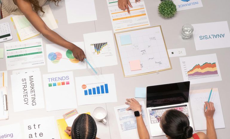 Top view of a team collaborating on marketing strategy and analysis papers.