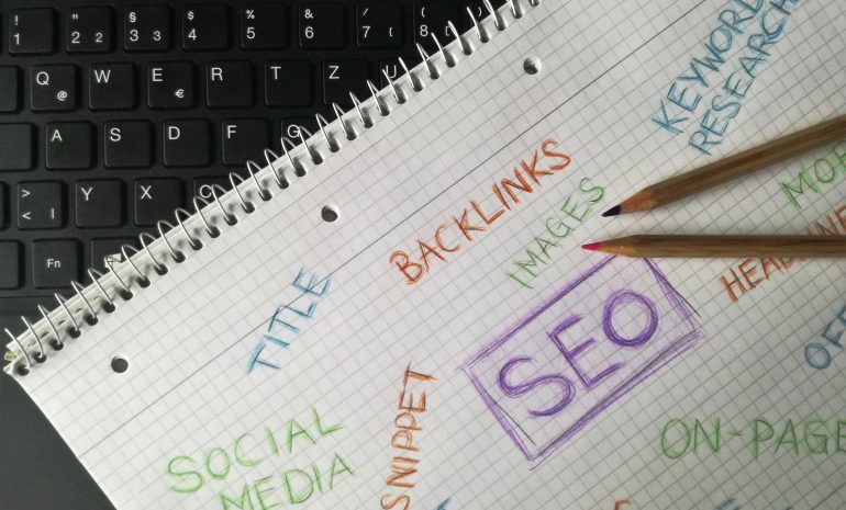 Close-up of notebook with SEO terms and keywords, highlighting digital marketing strategy.